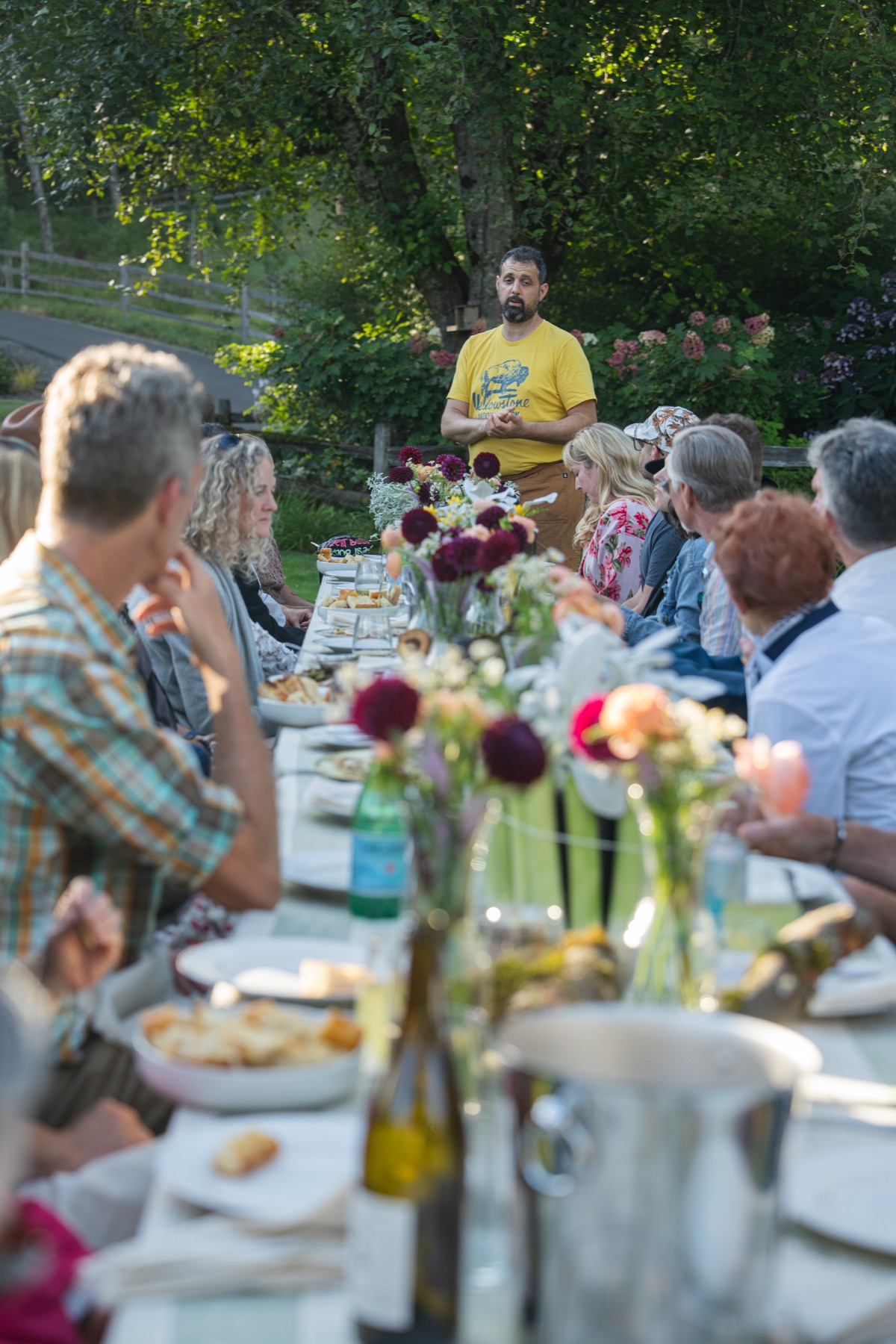 The dinner host speaking to guests gathered around the table